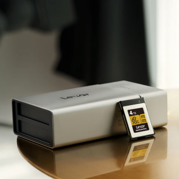 A Lexar memory card positioned next to portable tech gear, emphasizing the importance of dedicating specific cards to specific cameras to avoid database incompatibilities.